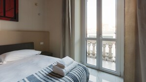 A hotel room with a bed, a window with a view of a building, and a curtain. - GuestHost - Bright APT with balcony- Milan Piazzale Loreto (Milano)