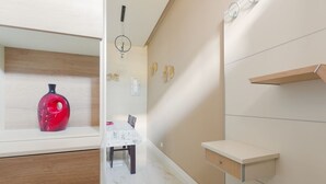 A modern kitchen with a white countertop, a red vase, and a dining area with a table and chairs. - GuestHost - Bright APT with balcony- Milan Piazzale Loreto (Milano)