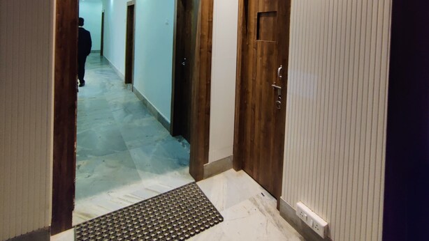 Un pasillo con paneles de madera, una puerta y un felpudo en la entrada.