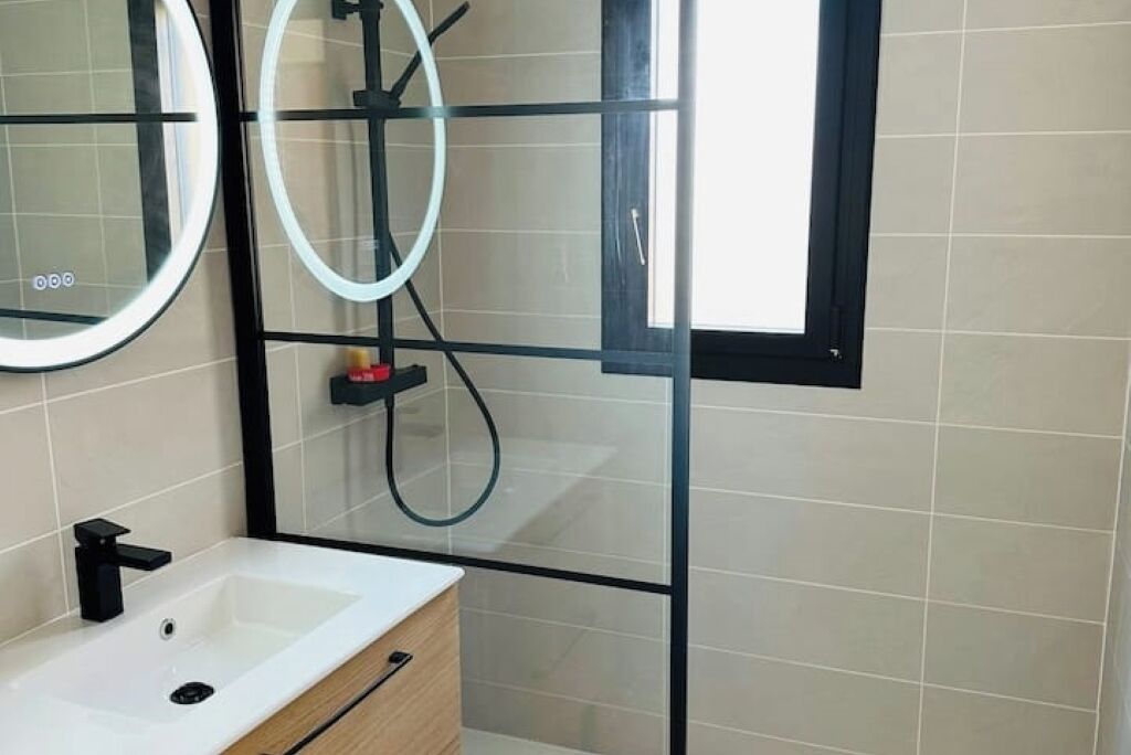 A bathroom with a white sink, a mirror, and a shower area.