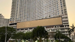 A tall, modern high-rise building with a grid of windows and balconies.