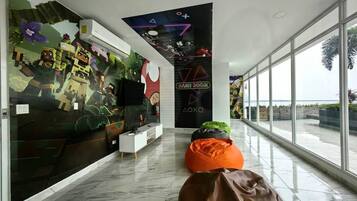 Een modern interieur met een groot raam, een muurschildering en een bordje 'Game Room'.