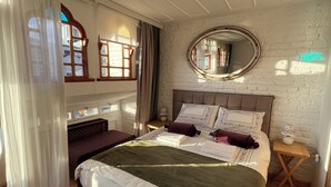 A bedroom with a large bed, a nightstand, a mirror, and a window with curtains. - Levant Pension de Luxe  (Istanbul)