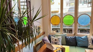 A cozy room with a wooden table, a laptop, a potted plant, and a green sofa with cushions. - Levant Pension de Luxe  (Istanbul)