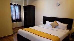 A hotel room with a large bed, a wardrobe, and a window with curtains. - Hotel RAAJASGRAND (Tirupati)