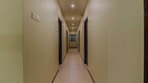 A long, narrow hallway with doors on both sides and a light-colored floor. - Hotel RAAJASGRAND (Tirupati)