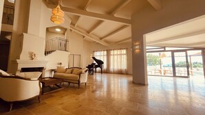 A spacious living room with a grand piano, a fireplace, and a balcony with outdoor seating. - La Réserve Provence (Vaugines)