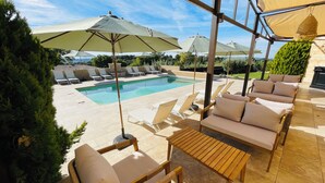 A poolside area with lounge chairs, umbrellas, and a wooden table. - La Réserve Provence (Vaugines)