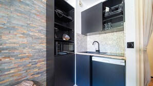 A compact kitchen with a built-in oven, a sink, and a microwave.