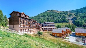 A multi-story hotel with balconies and a mountainous backdrop.