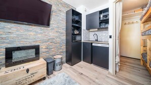 A compact kitchen with a stone wall, black cabinetry, and a built-in microwave.