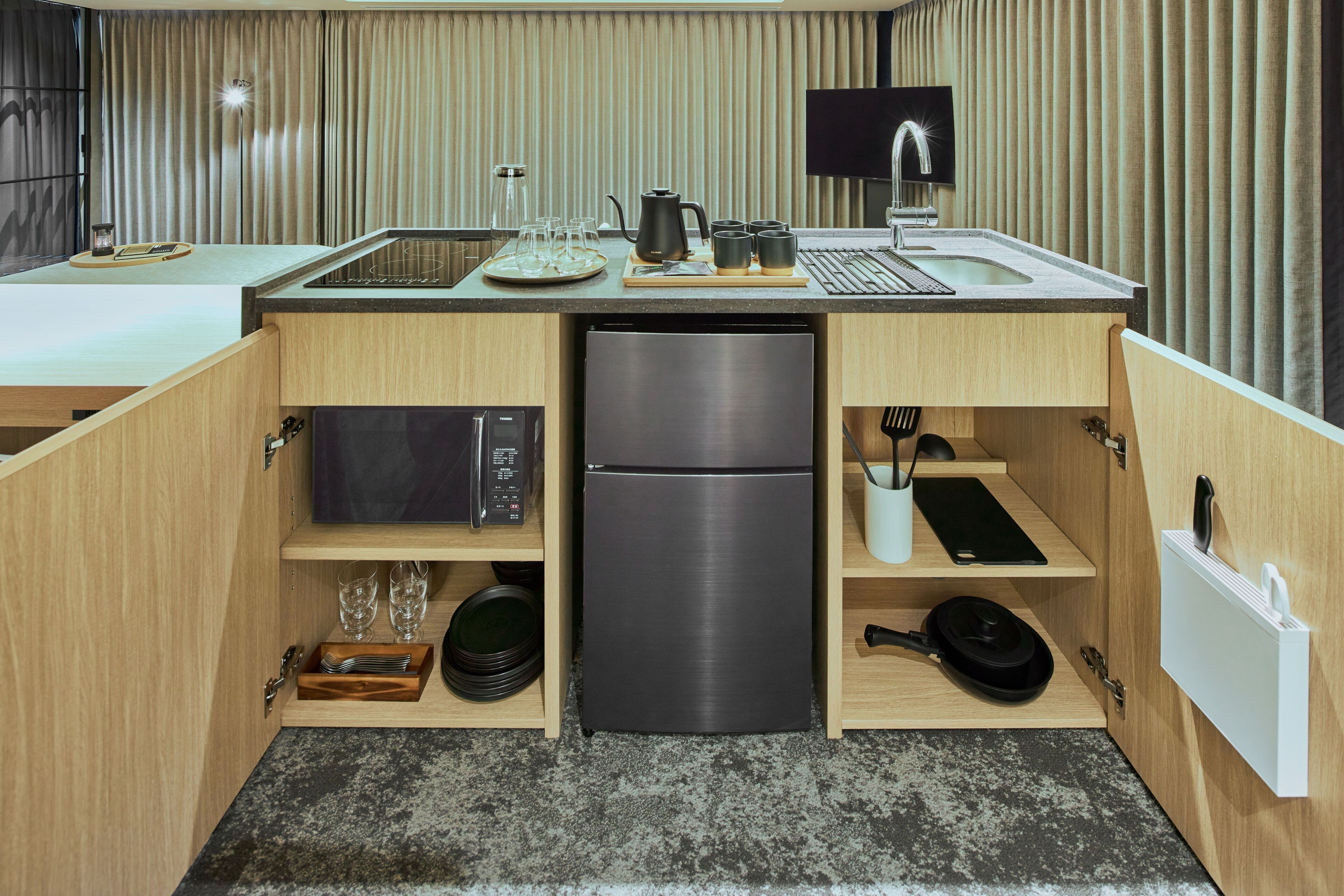 A compact kitchen with a built-in refrigerator, microwave, and a small sink.