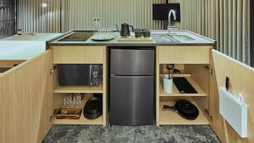 A compact kitchen with a built-in refrigerator, microwave, and a small sink.