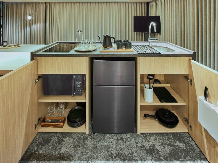 A compact kitchen with a built-in refrigerator, microwave, and a small sink.