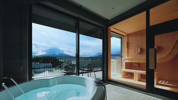 Un espace spa moderne doté d’un bain à remous, d’un sauna en bois et d’un balcon offrant une vue sur la montagne.