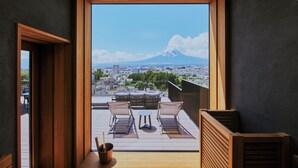 Un balcon offrant une vue sur le mont Fuji, des meubles en bois et un panorama sur la ville.