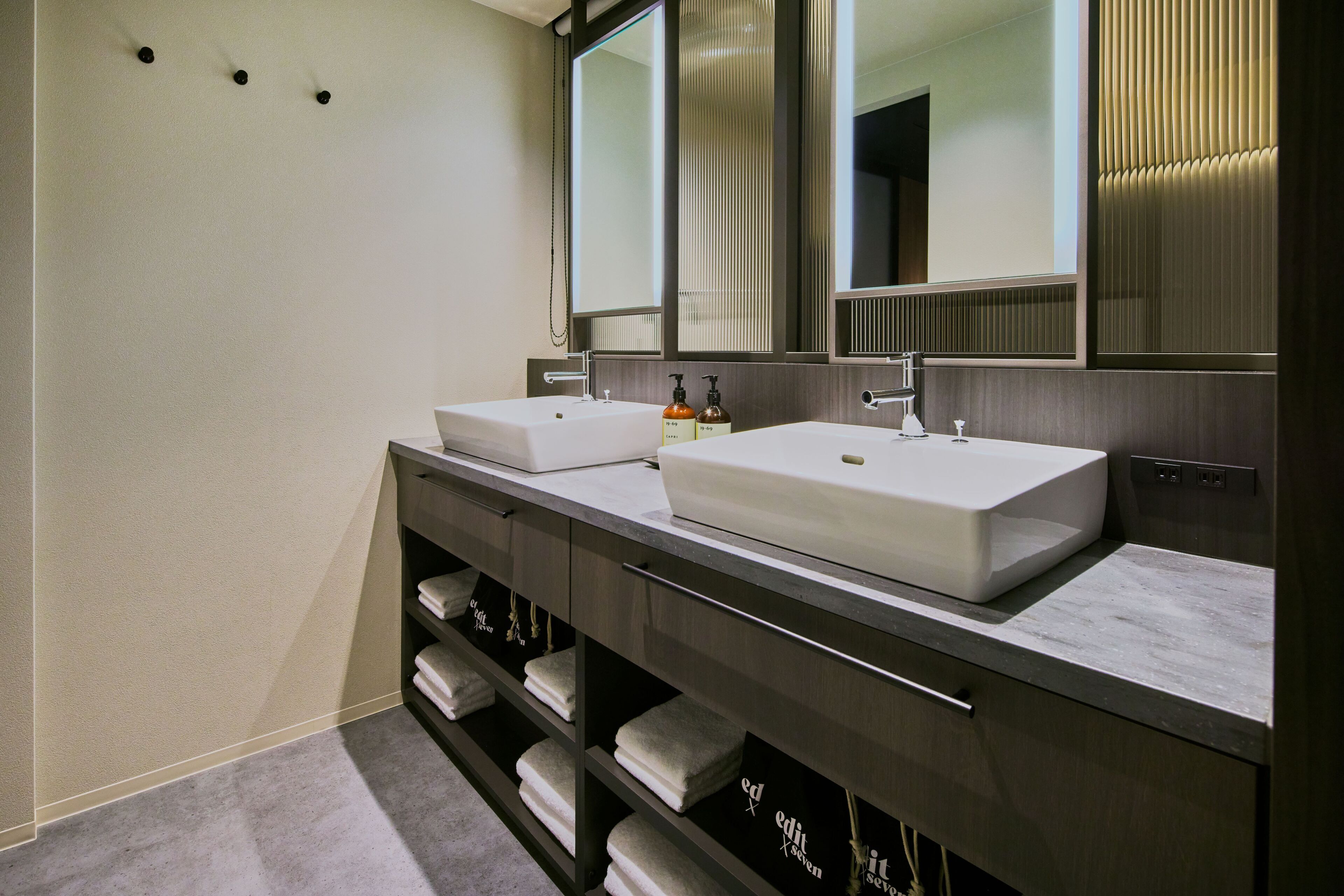 A modern bathroom with two sinks, a large mirror, and a towel rack.