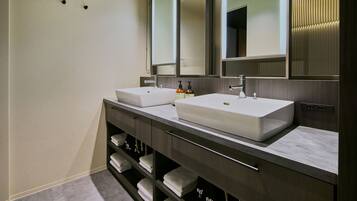 A modern bathroom with two sinks, a large mirror, and a towel rack.