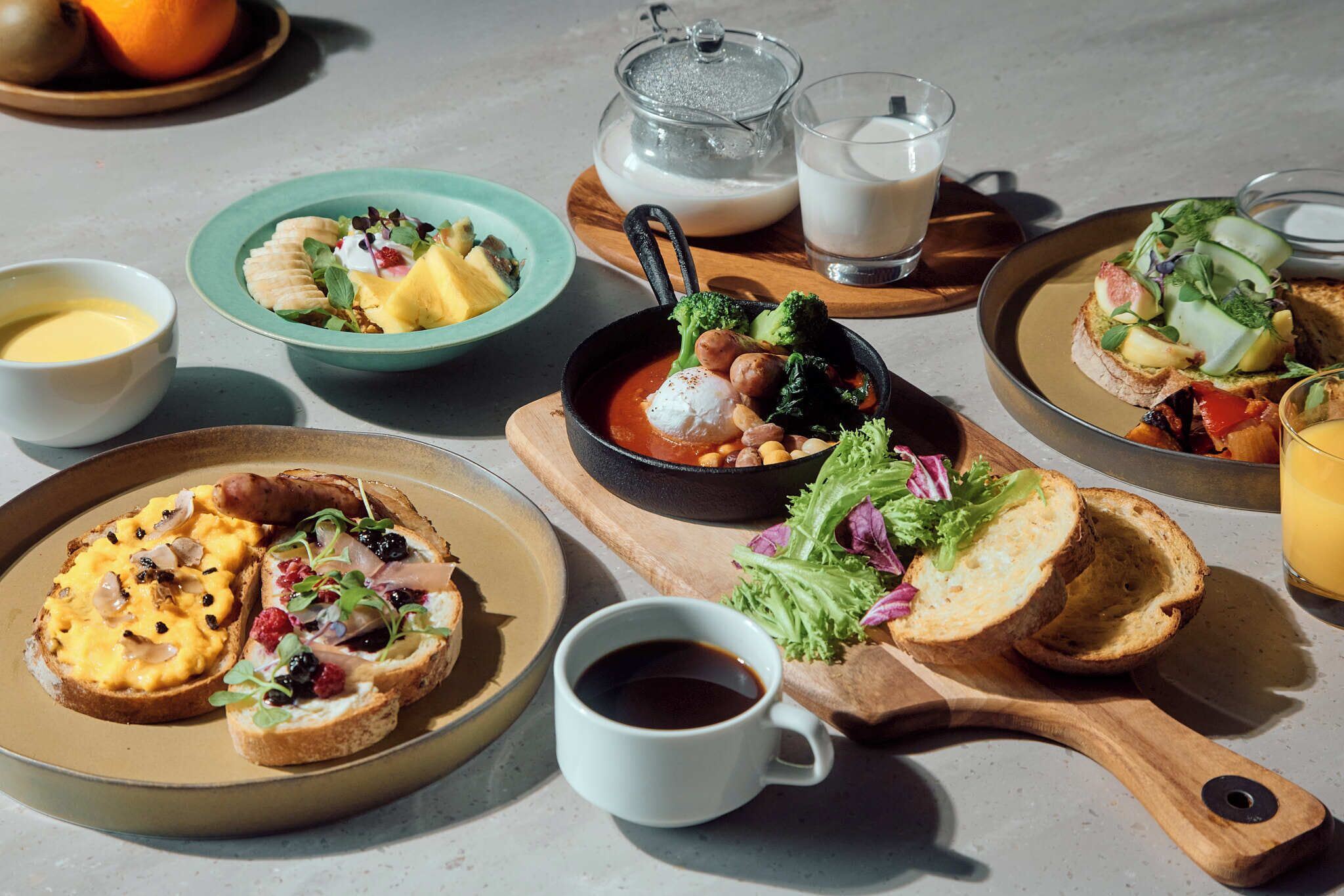 A variety of breakfast dishes on plates, a cup of coffee, and a glass of milk on a table.