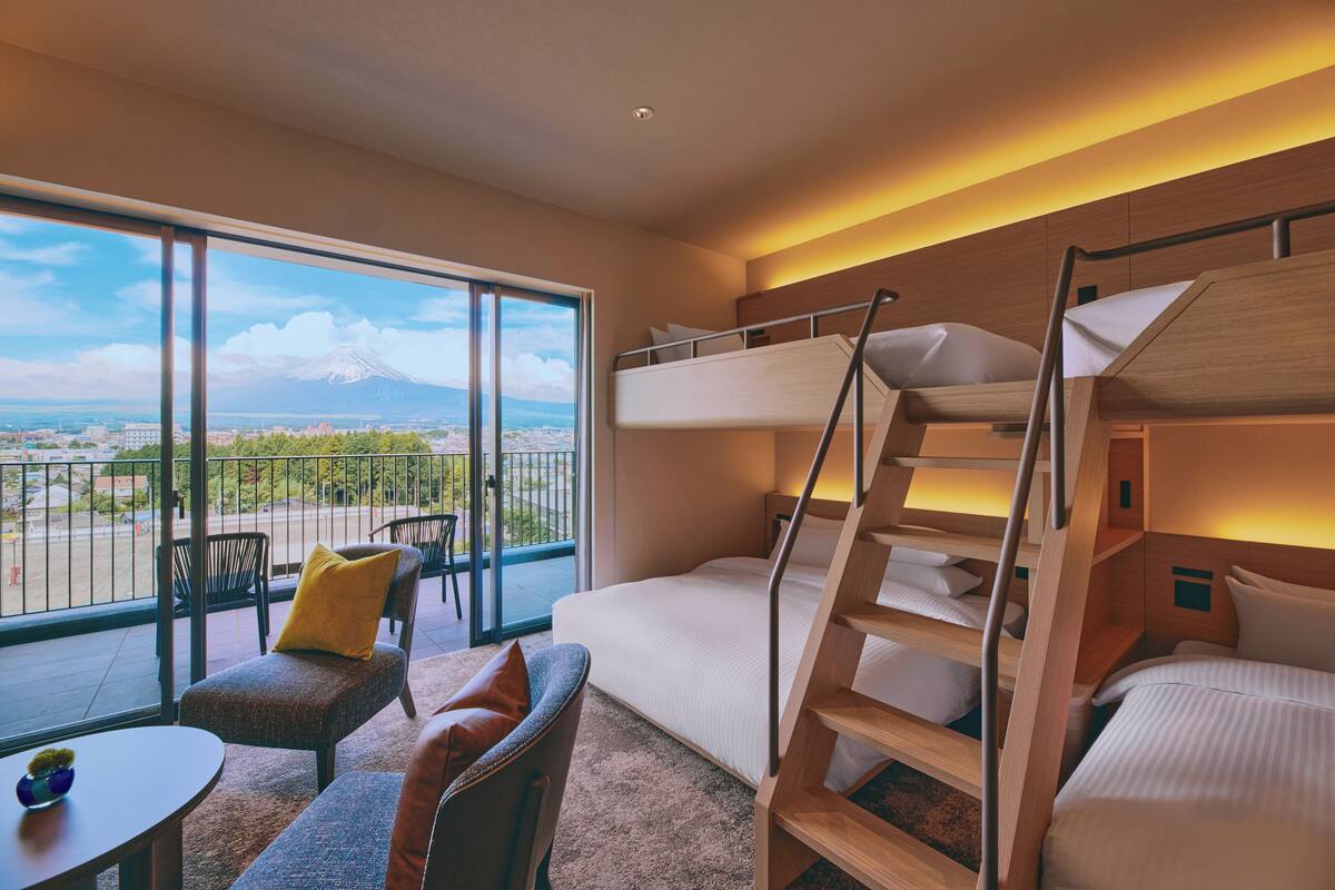 Ein Hotelzimmer mit Balkon, Etagenbetten, einer Couch und einem kleinen Tisch.