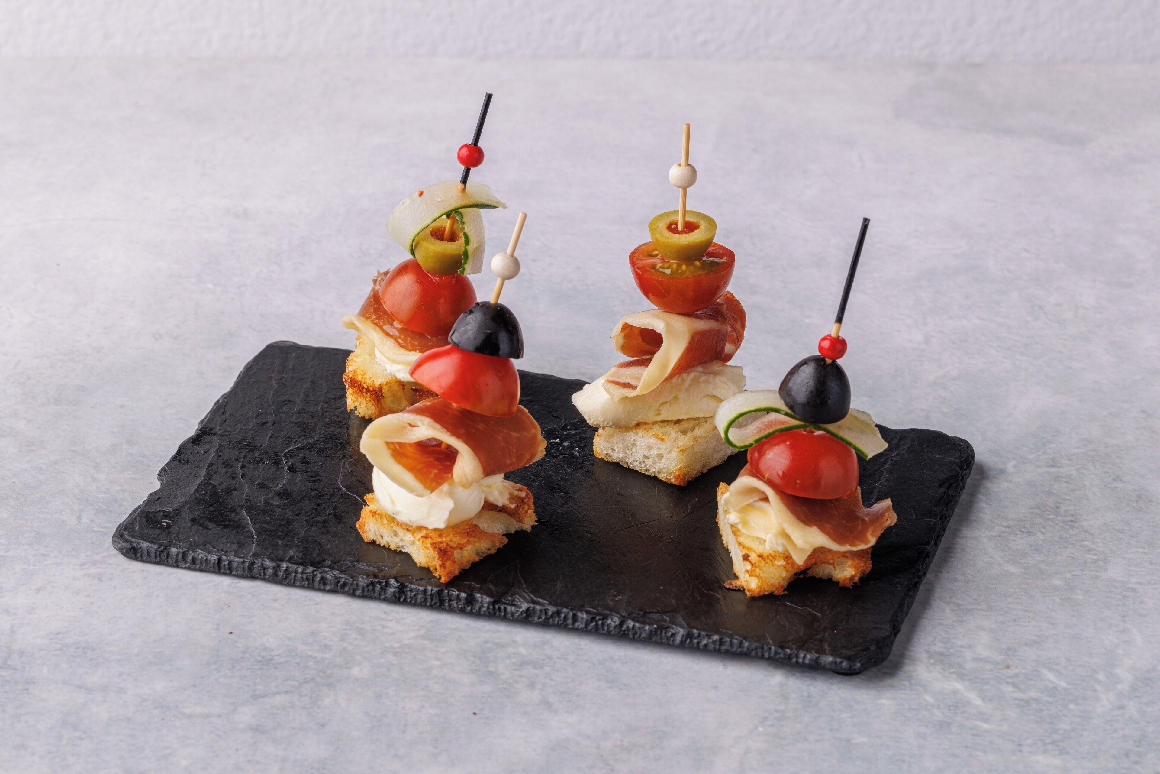 Three appetizers on a slate serving board.