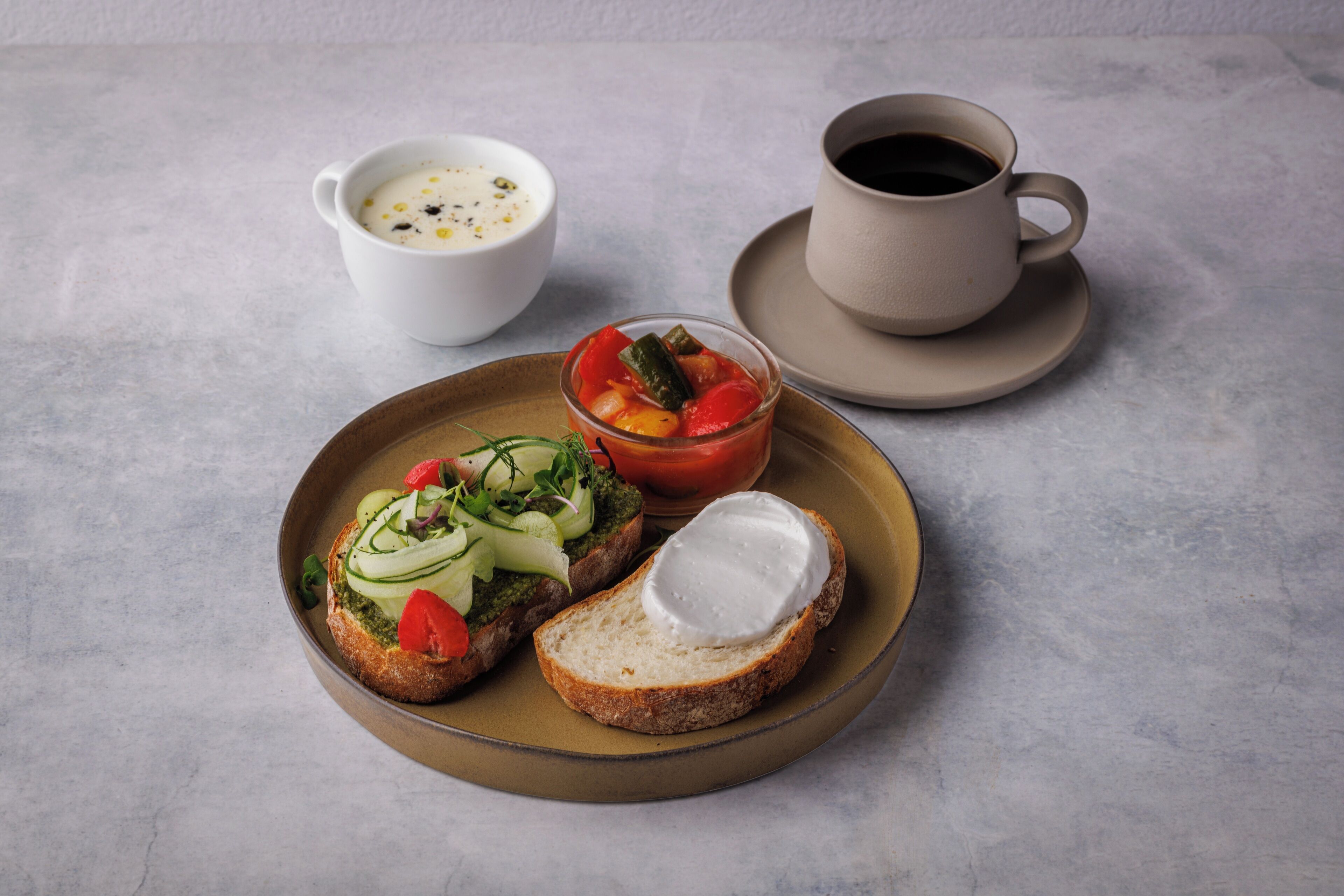 A plate with bruschetta and a cup of coffee on a table.