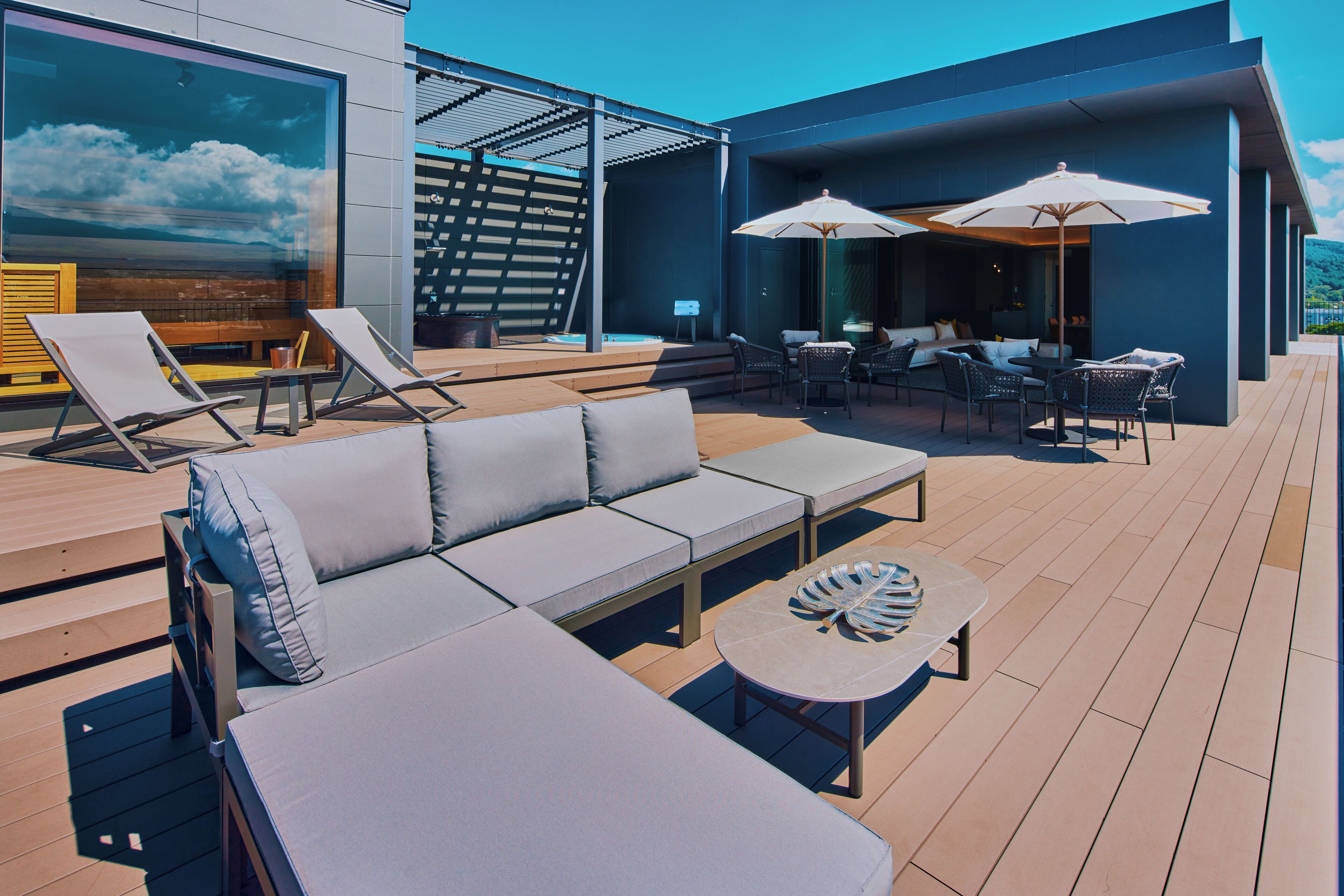 A modern outdoor lounge area with a sofa, chairs, and a table.