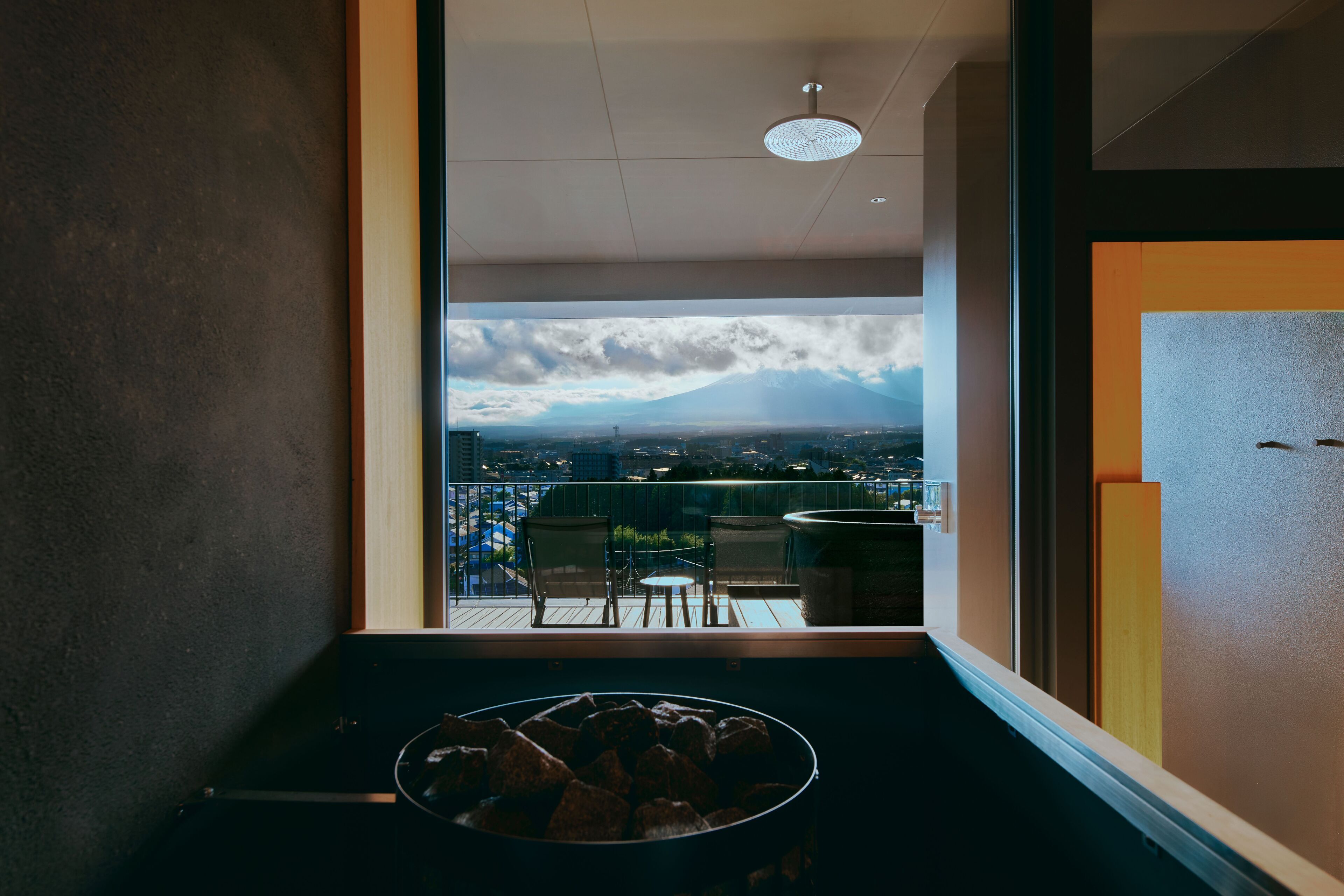 A balcony with a view of a mountain, a fire pit, and outdoor furniture.