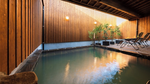 A pool area with wooden walls, lounge chairs, and potted plants. - HOTEL MEGURI (Usa)