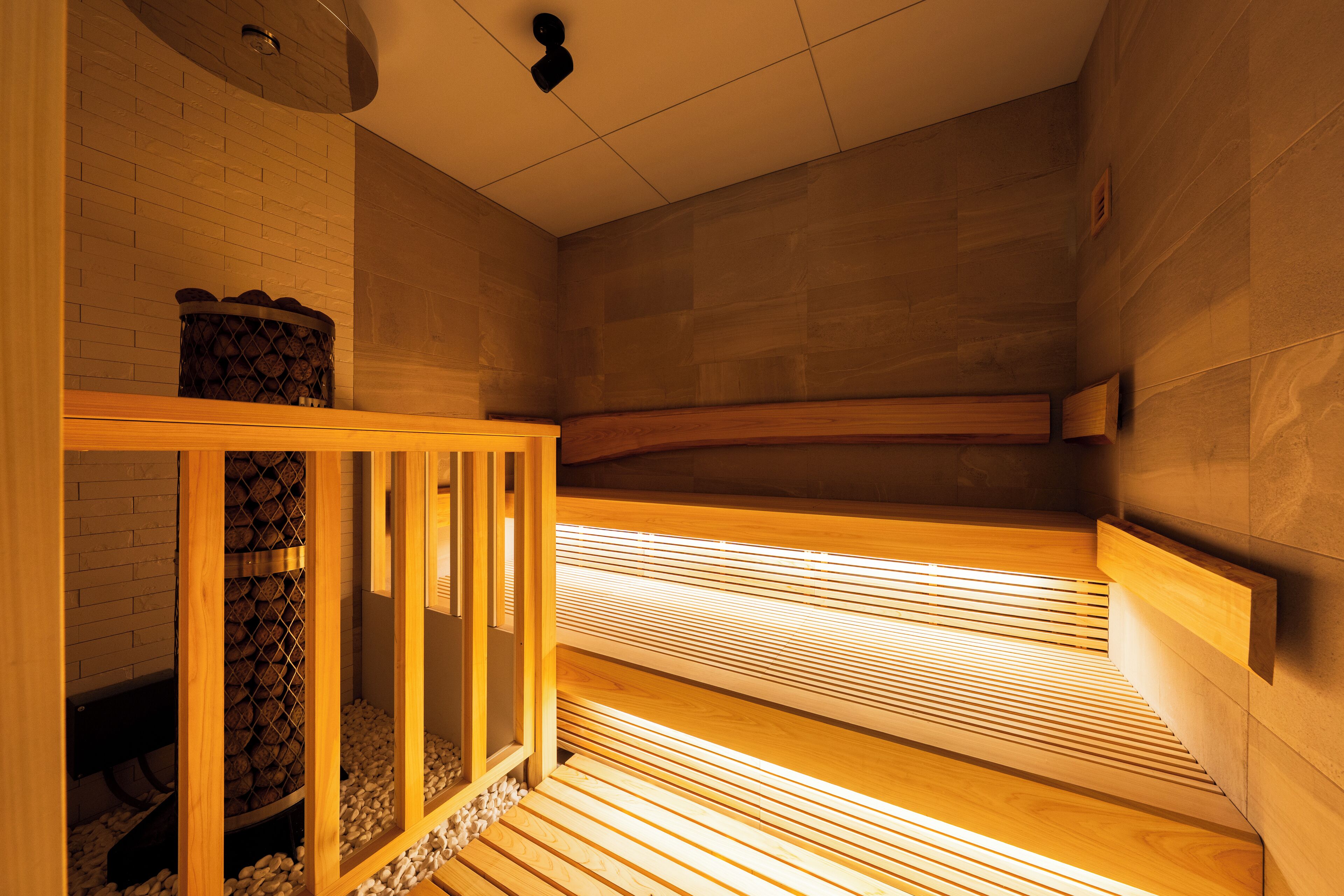 Una sauna con bancos de madera y un banco con una cesta de leña.