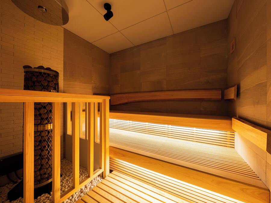 Una sauna con bancos de madera y un banco con una cesta de leña.