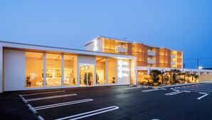 A modern hotel with a spacious parking lot and large glass windows. - HOTEL MEGURI (Usa)