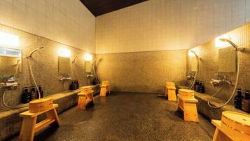 Un baño moderno con múltiples cabezales de ducha, taburetes de madera y suelo de baldosas.