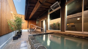 A swimming pool with stone steps, wooden walls, and a view of the sky. - HOTEL MEGURI (Usa)