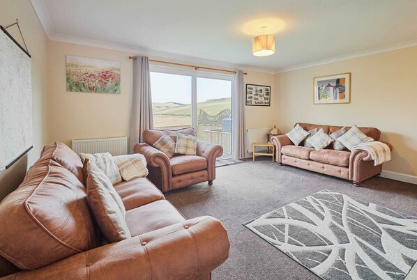 Relax in a serene space with a large window offering countryside views, two comfortable sofas, and ambient lighting.