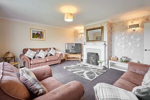 Relax in a cozy seating area with a sofa, armchairs, and a fireplace.