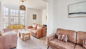 A spacious living room with a large window, a wooden coffee table, and two sofas with cushions. - Host Stay Bedford Street (Brighton)