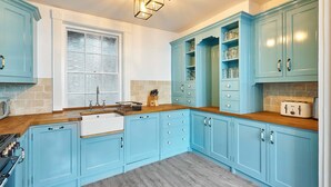 A kitchen with light blue cabinets, a wooden countertop, a window with frosted glass, and a built-in stove. - Host Stay Bedford Street (Brighton)