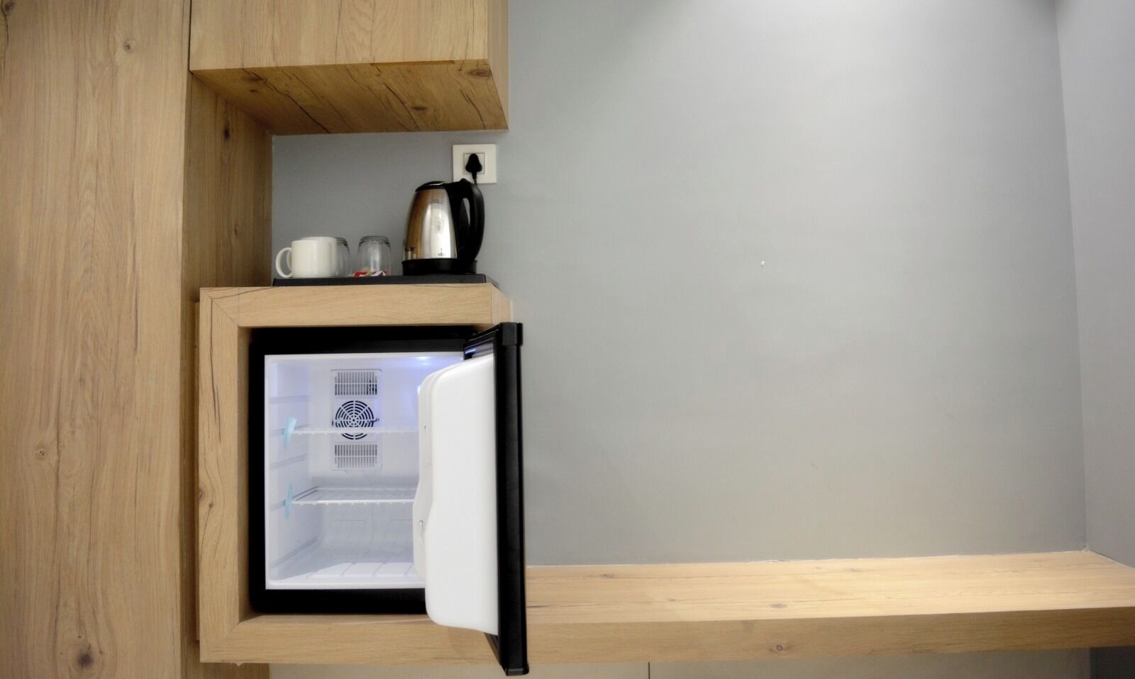 Ett kompakt kök med ett inbyggt kylskåp, en kaffebryggare och en vattenkokare på bänkskivan.