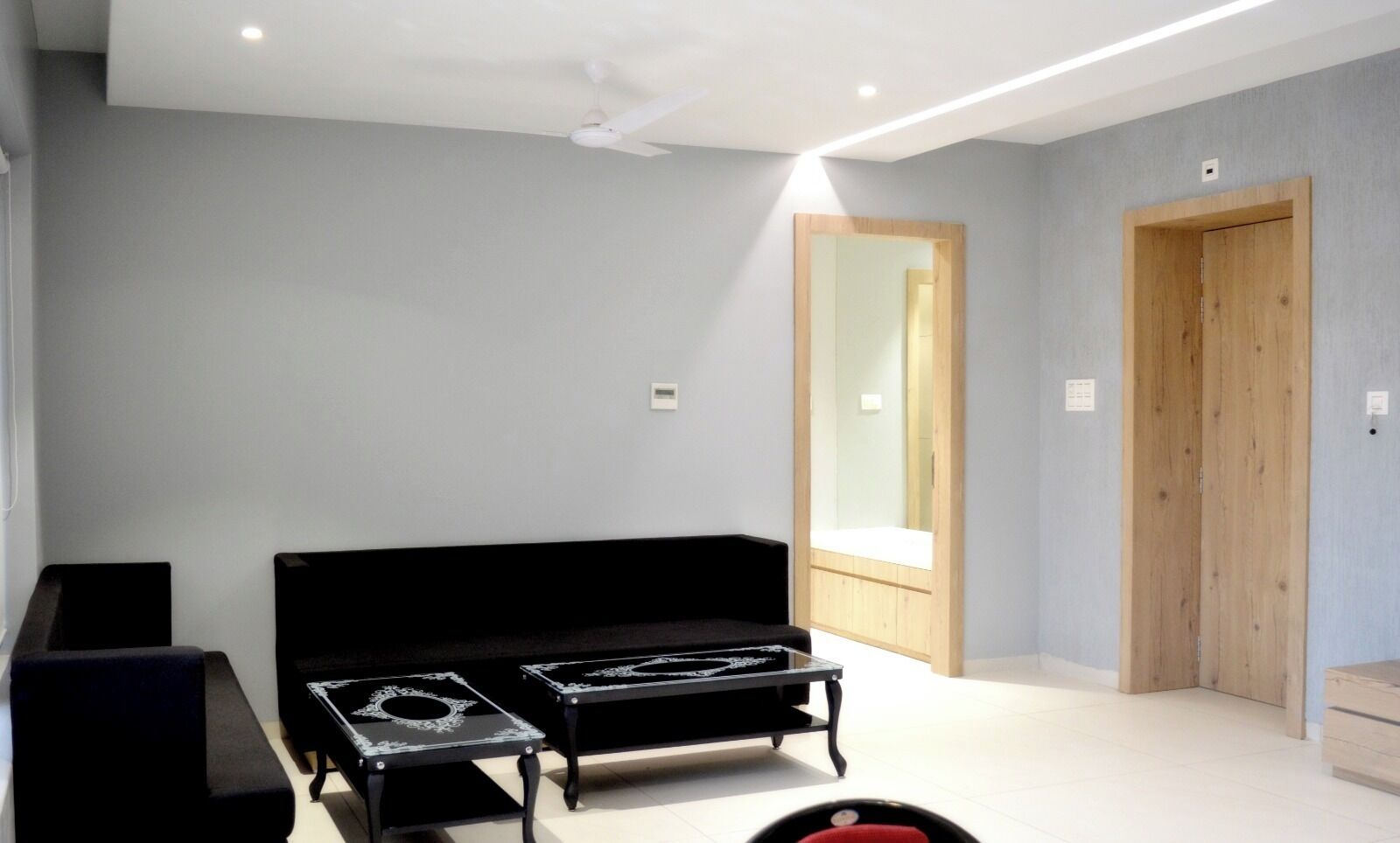 A modern living room with a black sofa, a small table, and a wooden door.