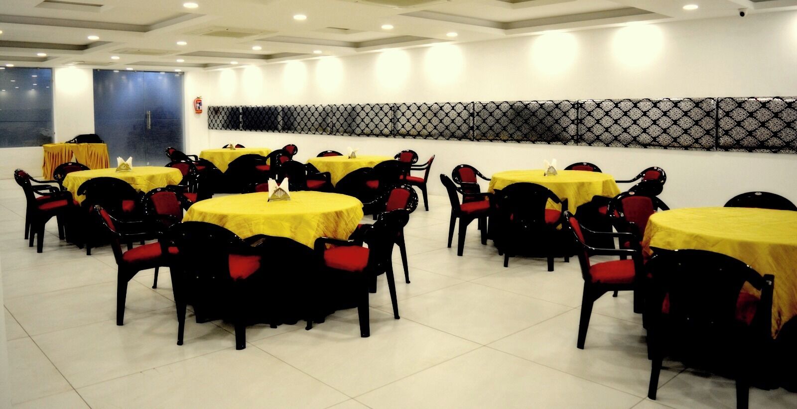 A conference room with multiple tables and chairs, arranged in rows.