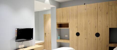 A modern bedroom with a bed, a TV, and wooden wardrobe with shelves.