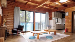 Un intérieur en bois comprenant une table à manger, des chaises et un coin cuisine.