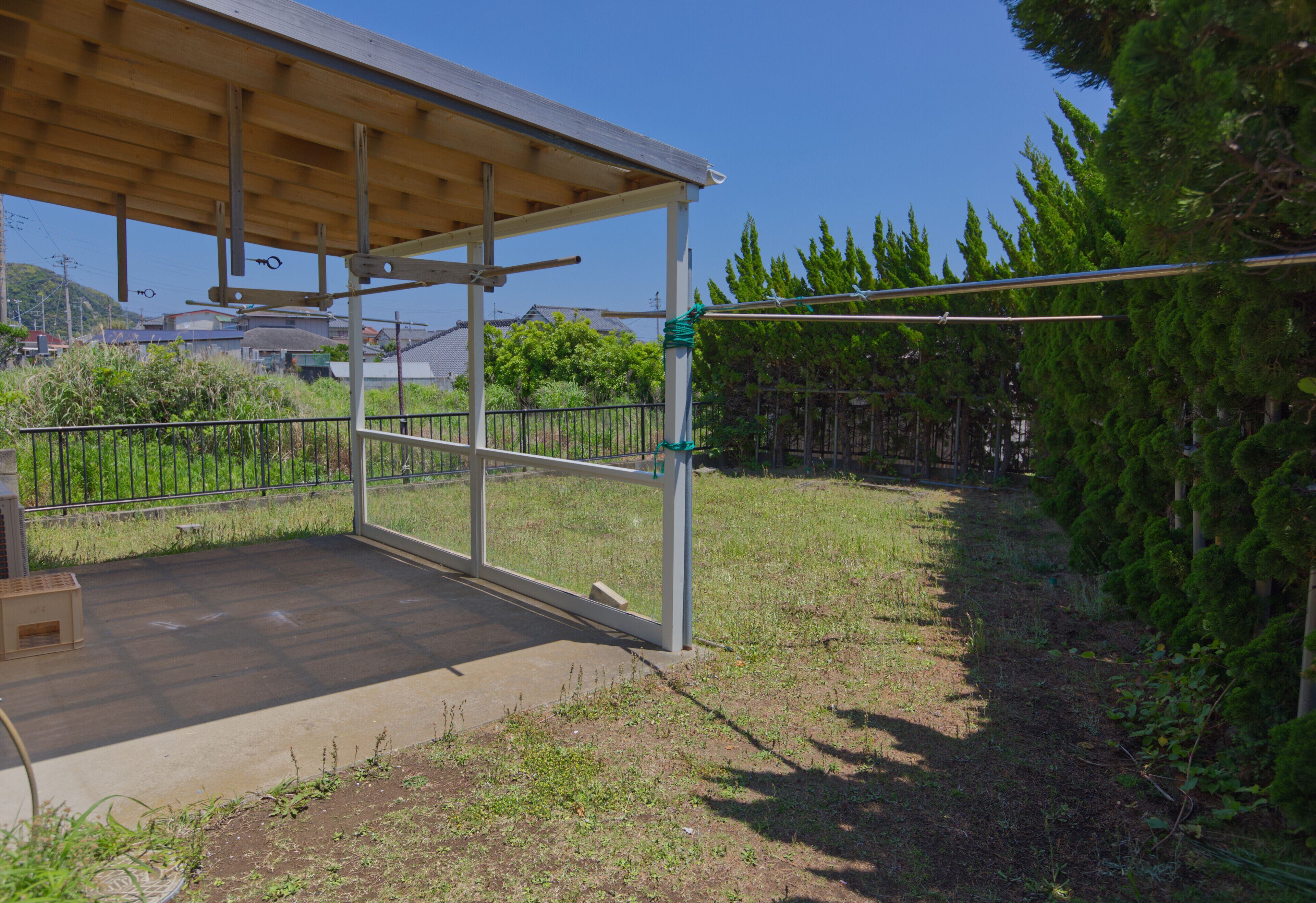 An outdoor covered patio area with a wooden deck, metal railing, and a view of a residential neighborhood.
