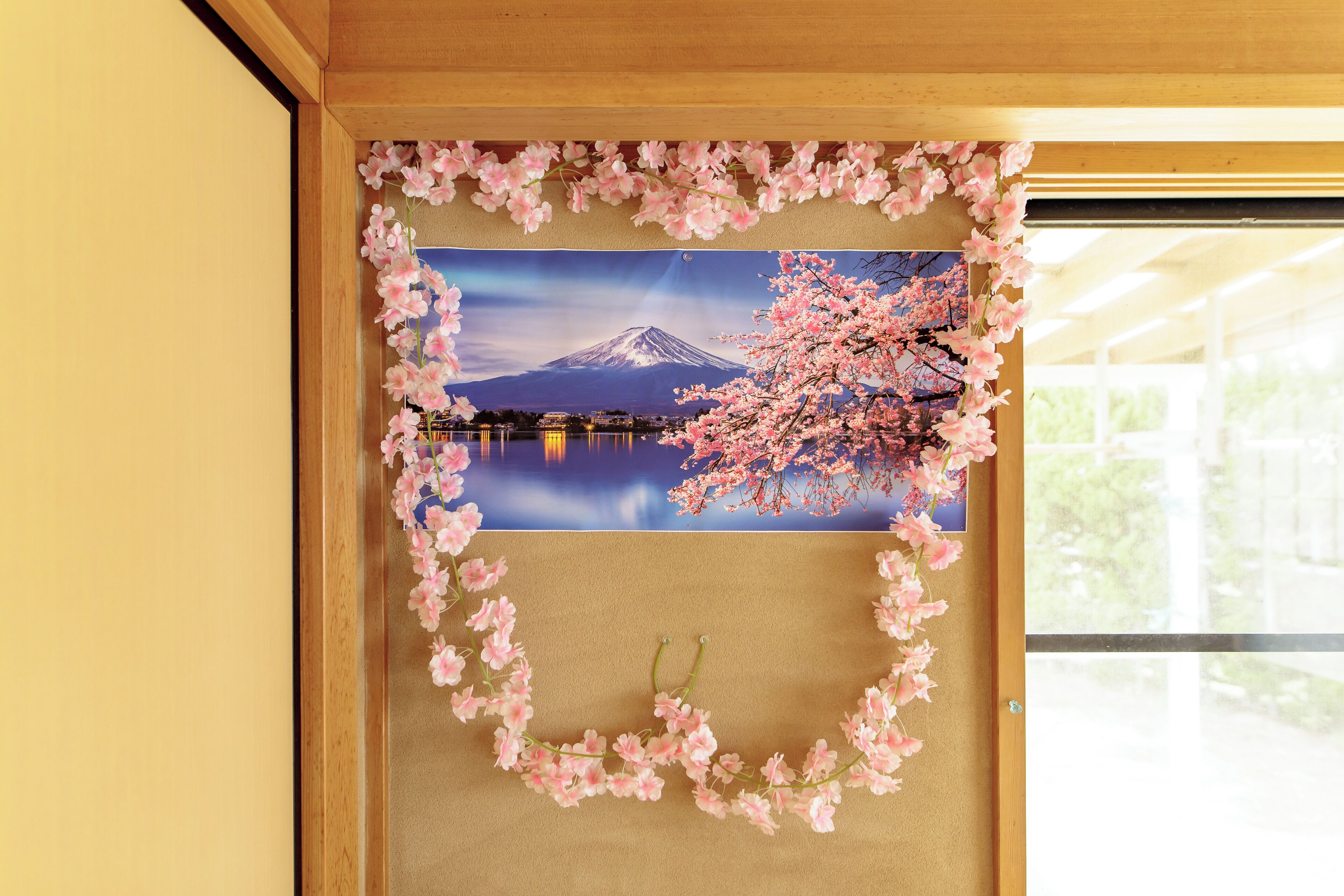 Une photographie encadrée du mont Fuji, avec des fleurs de cerisier en arrière-plan, est accrochée à un mur de couleur beige.