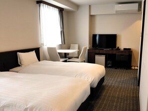 A hotel room with two beds, a desk with a TV, a chair, and a small refrigerator. - BANDE HOTEL TEMPOZAN (Osaka)