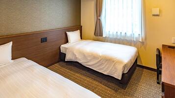 A hotel room with two beds, a wooden headboard, a carpeted floor, a window with curtains, and a desk with a chair.