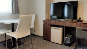 A hotel room with a desk, a chair, a television, a small refrigerator, and a trash bin. - BANDE HOTEL TEMPOZAN (Osaka)