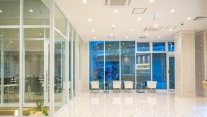 A modern lobby with glass walls, a marble floor, and a seating area with white chairs. - BANDE HOTEL TEMPOZAN (Osaka)