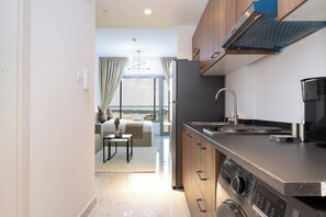 A modern kitchen with a built-in oven, a stainless steel sink, and a large window overlooking a balcony.